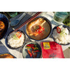 Lifestyle photograph of Thai Seafood Yellow Curry and bowls of rice and fresh chilis in outdoor setting.  