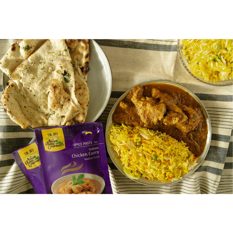 lifestyle photograph of traditional Indian cuisine, chicken curry with a side of yellow rice and garlic naan. 