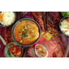 lifestyle photograph of Thai Cuisine, seafood red curry with a side of fresh chilis and two bowls of rice. 